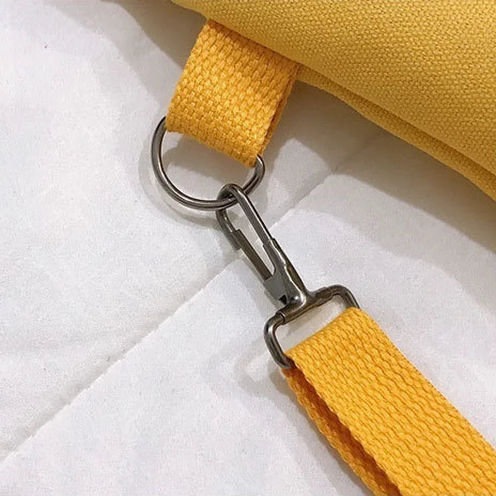 Close-up of the long strap clipped on: the lobster hook closed around the metal ring on the bag's webbing loop