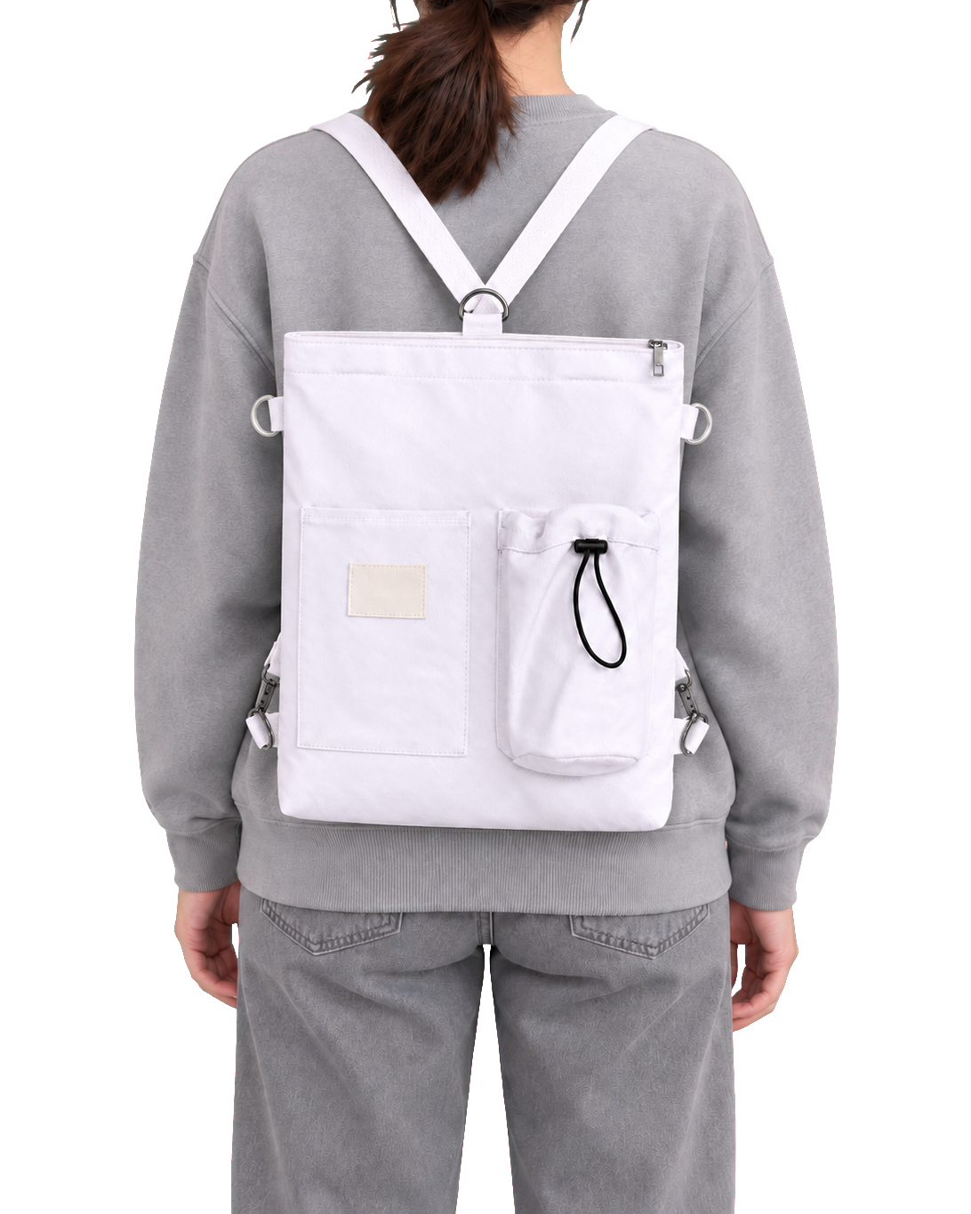 The same white tote worn on the back on both shoulders, the one long strap threaded through the ring at the top and clipped to the two bottom corners