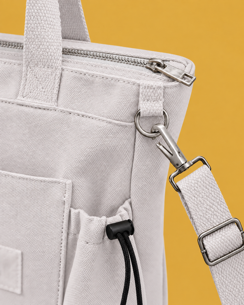 Close-up of the long strap's swivel hook clipped closed around the metal ring on the white tote